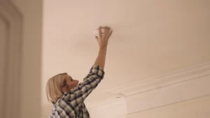 personne installant un détecteur de fumée au plafond